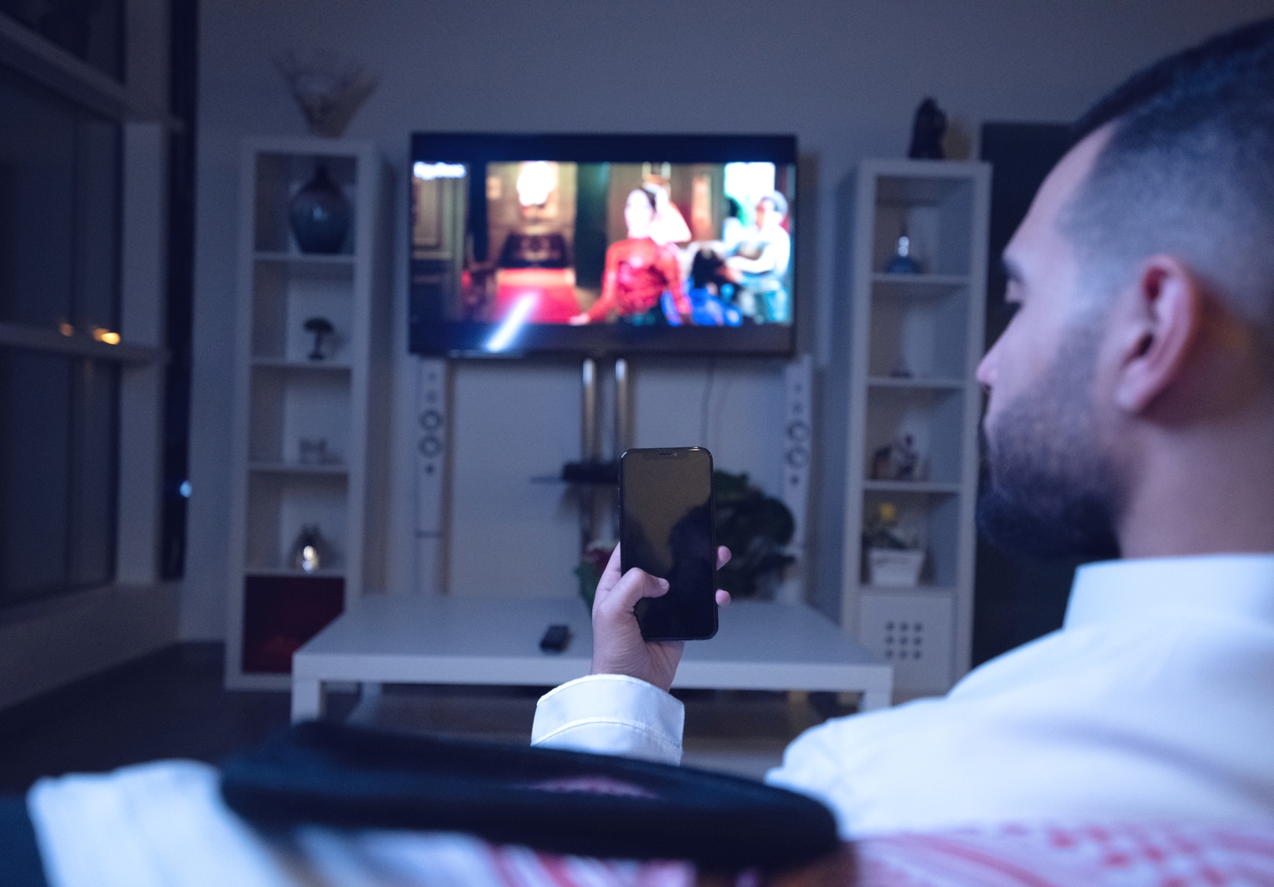Man with smart phone watching TV