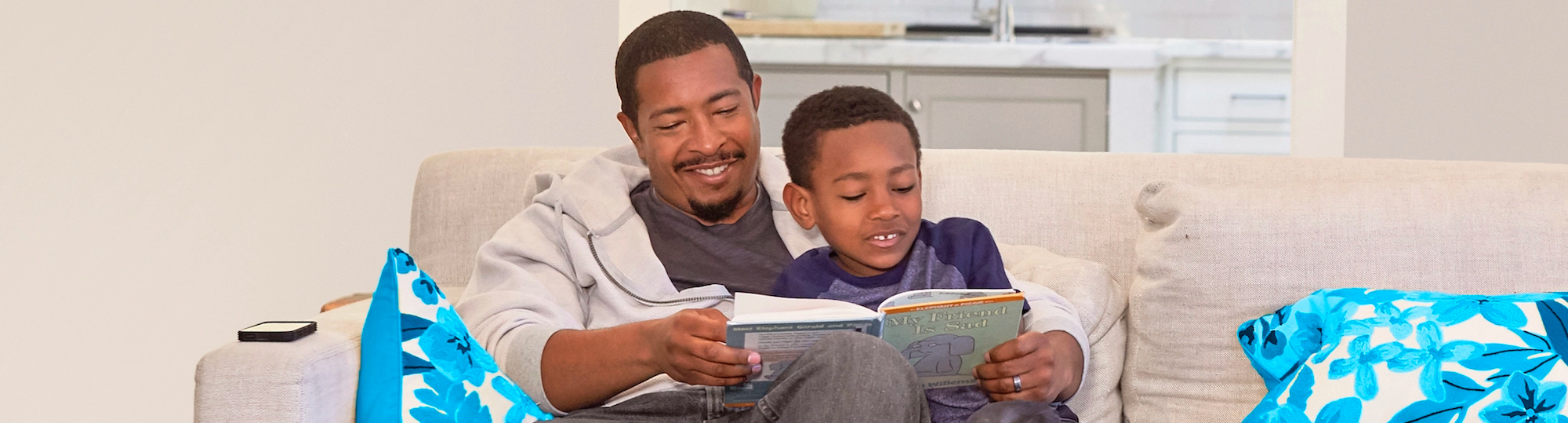 Father and son read book together on couch